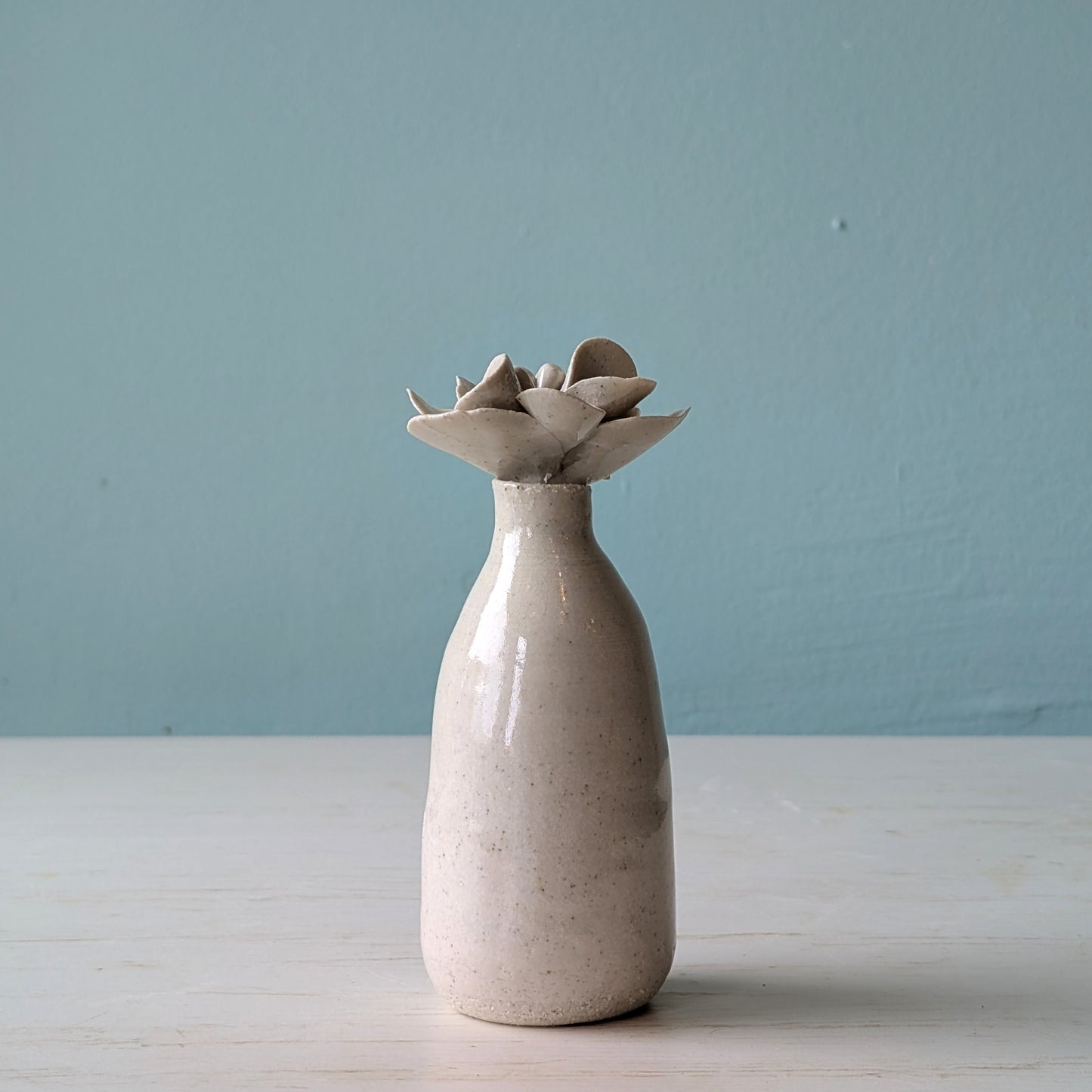 Ceramic bottle with a unique design on the lid on a light blue background