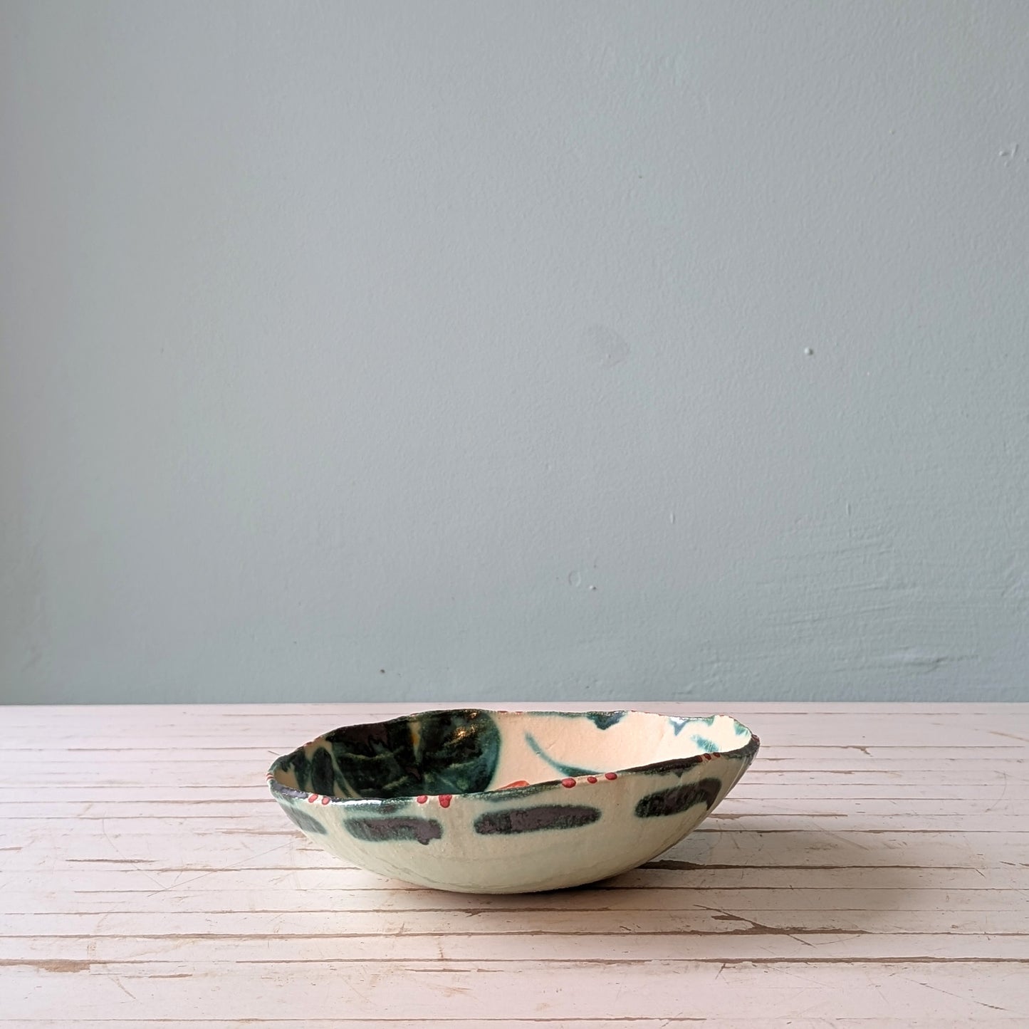 Ceramic bowl with floral patterns on a wooden surface and blue background.