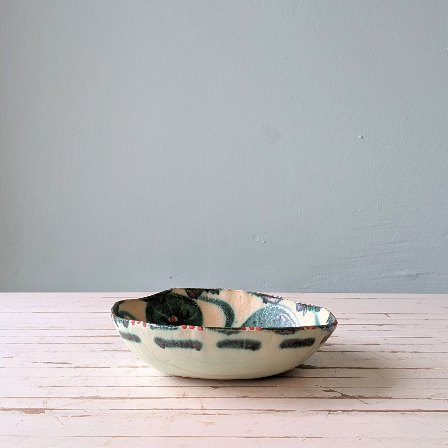 Ceramic bowl with floral design on a wooden surface and blue background