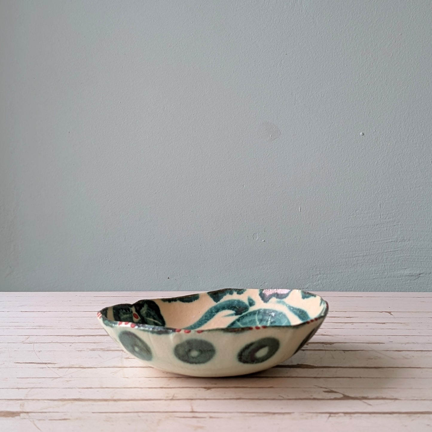 Ceramic bowl with a floral design on a wooden surface against a blue wall