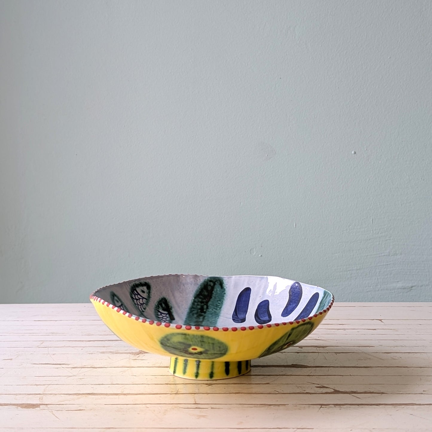 Colorful ceramic bowl on a wooden surface with a blue background