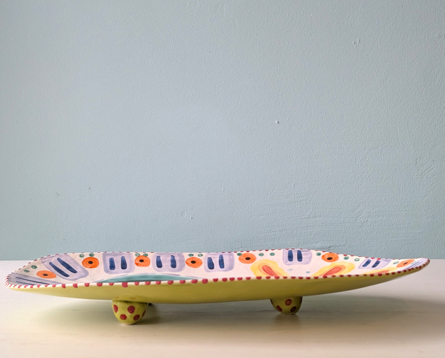 Decorative ceramic platter with colorful patterns on a light blue background