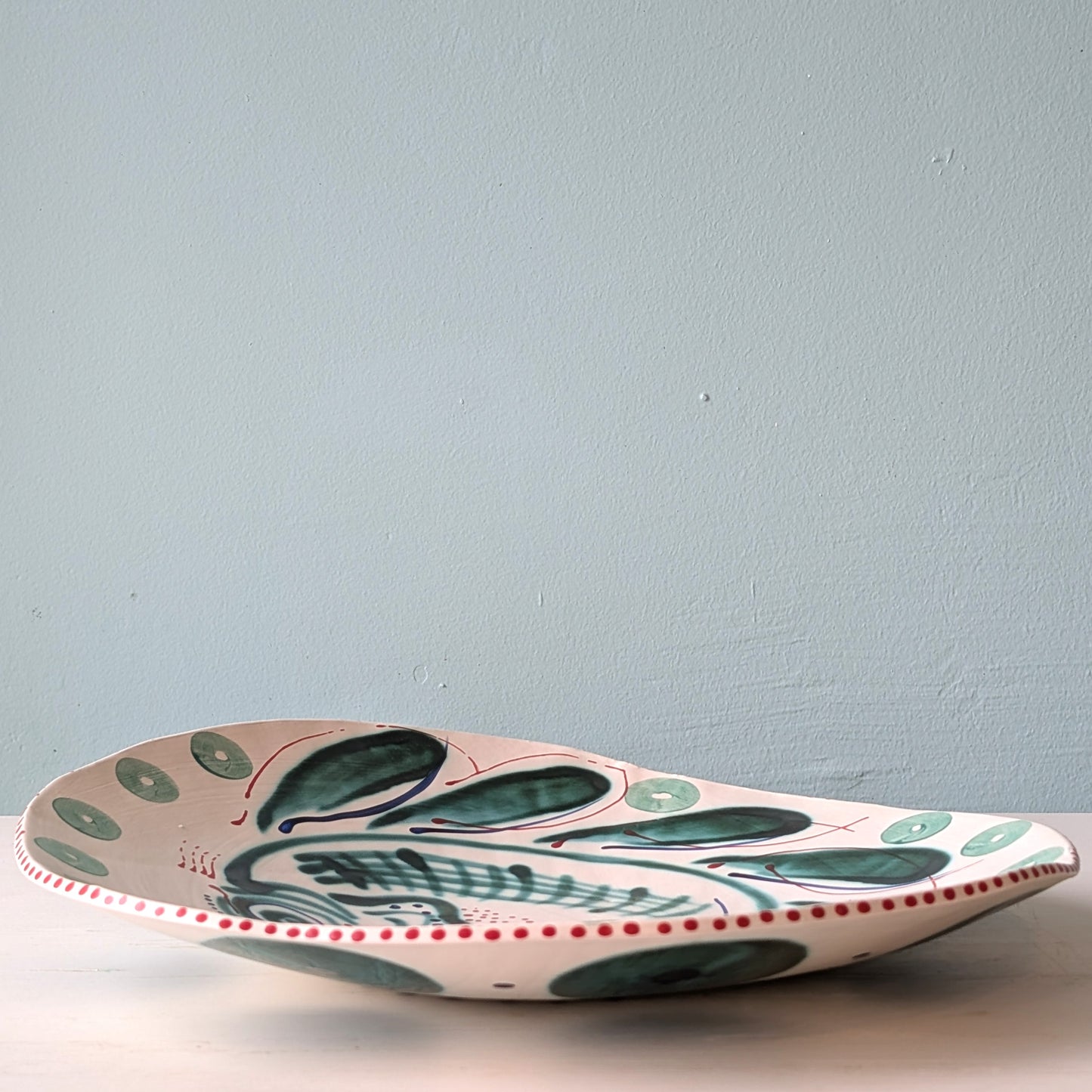 Ceramic platter with green fish design on a light blue background