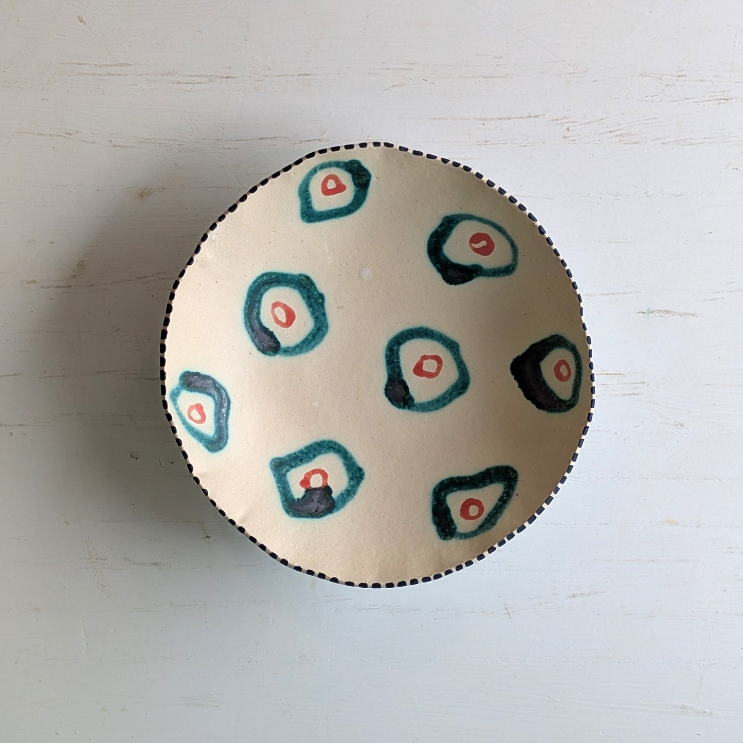 Round ceramic bowl with green abstract design on a white surface