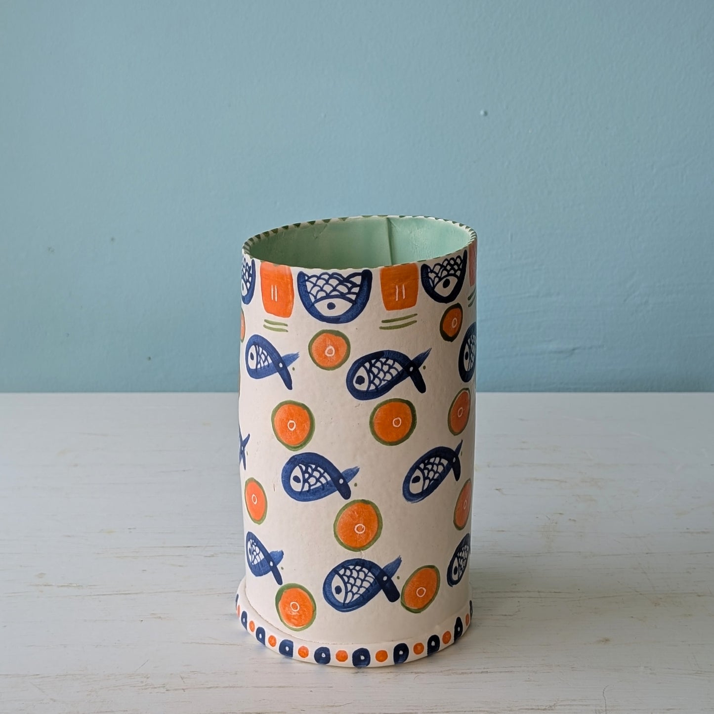 Cylindrical vase with fish pattern on a light blue background