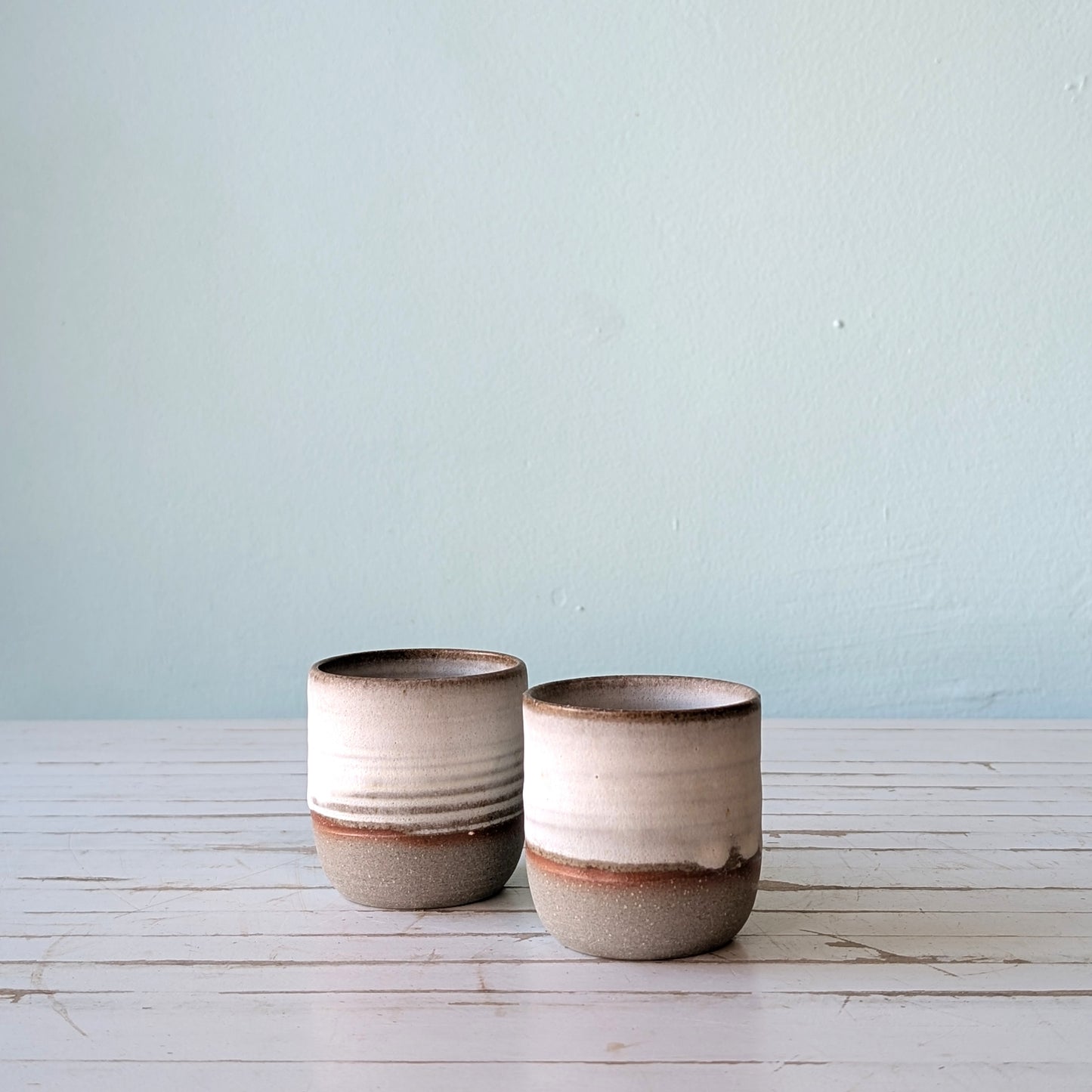 Front view of two ceramic espresso cups with dark stoneware and white slip