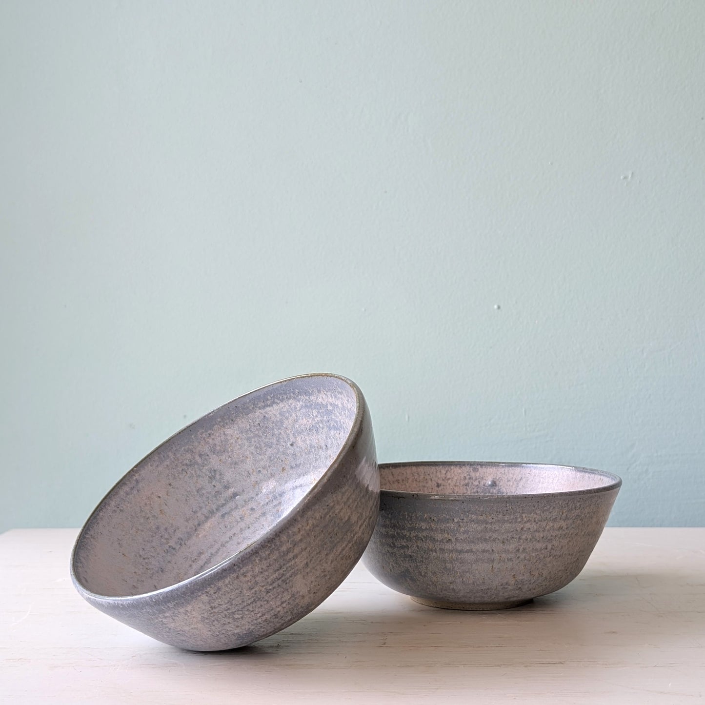 Two blue ceramic bowls on a light surface with a light blue background
