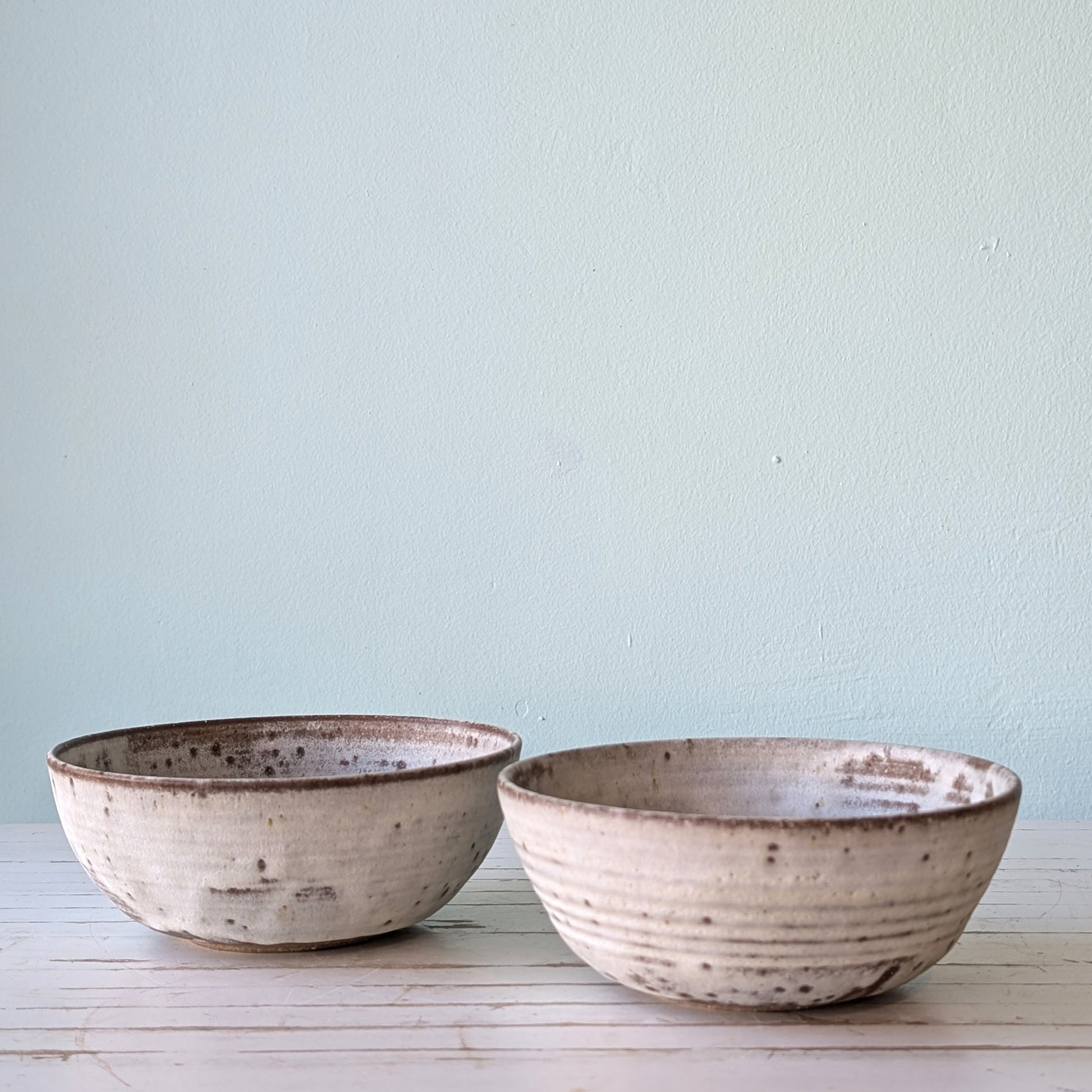 Frpnt view of two ceramic pasta bowls made from dark stoneware with white slip exterior