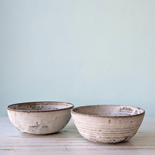 Frpnt view of two ceramic pasta bowls made from dark stoneware with white slip exterior