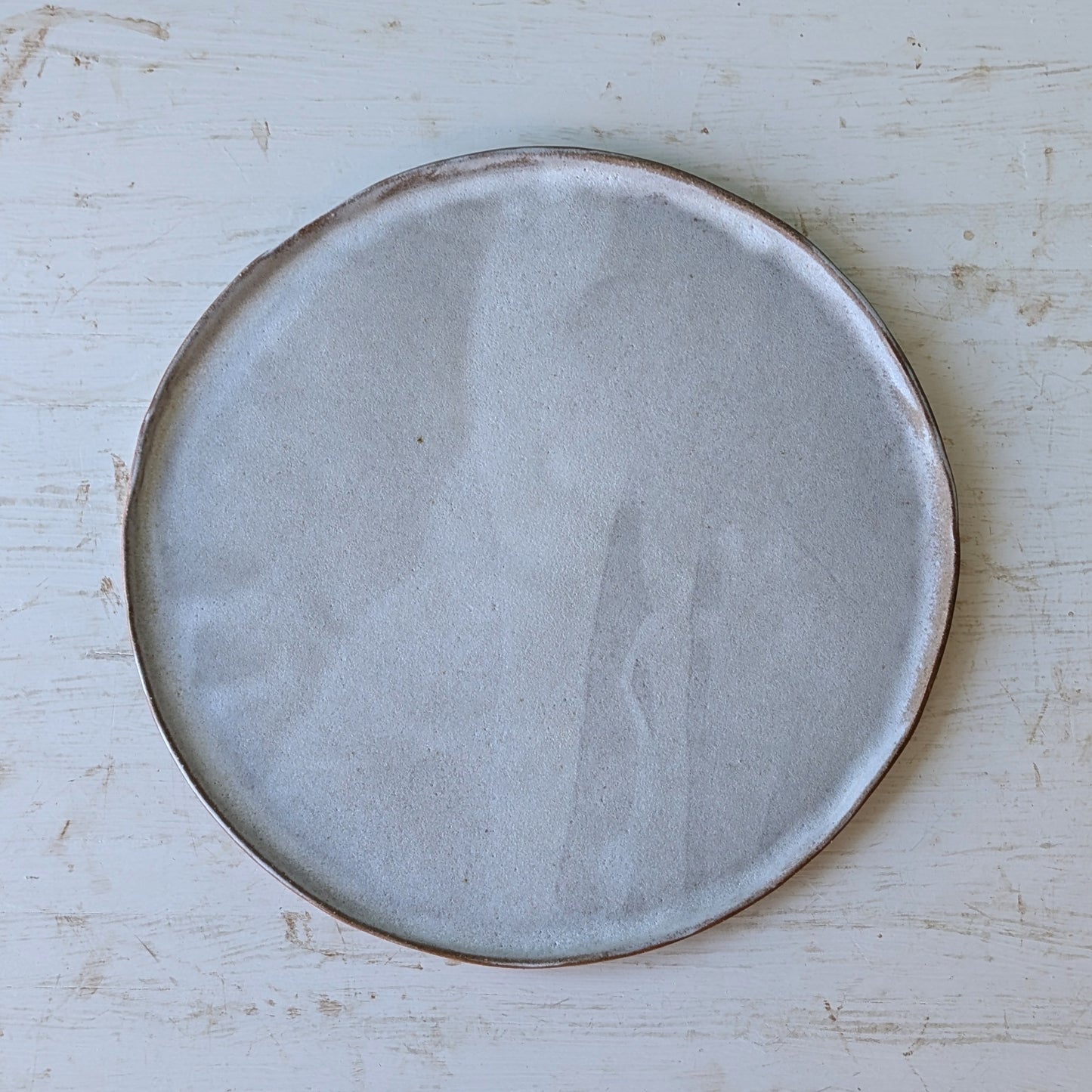 Round ceramic plate with a textured surface on a light wooden table