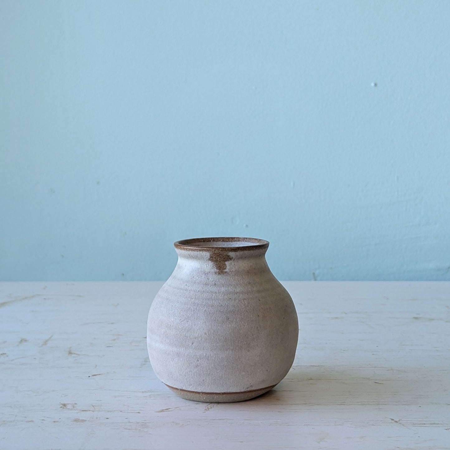 Ceramic vase on a light wooden surface with a light blue background