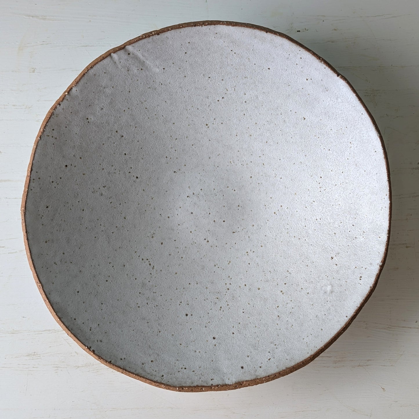Round ceramic bowl with a speckled white surface on a white background