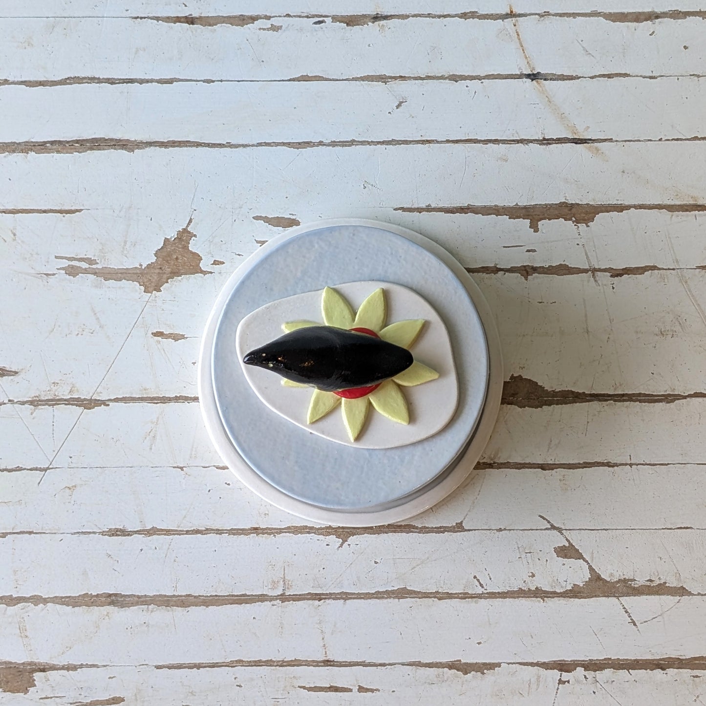 Top view of a butter dish with a black and yellow design on a wooden surface