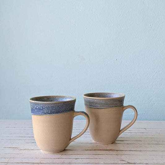 two ceramic mugs with blue glaze rim