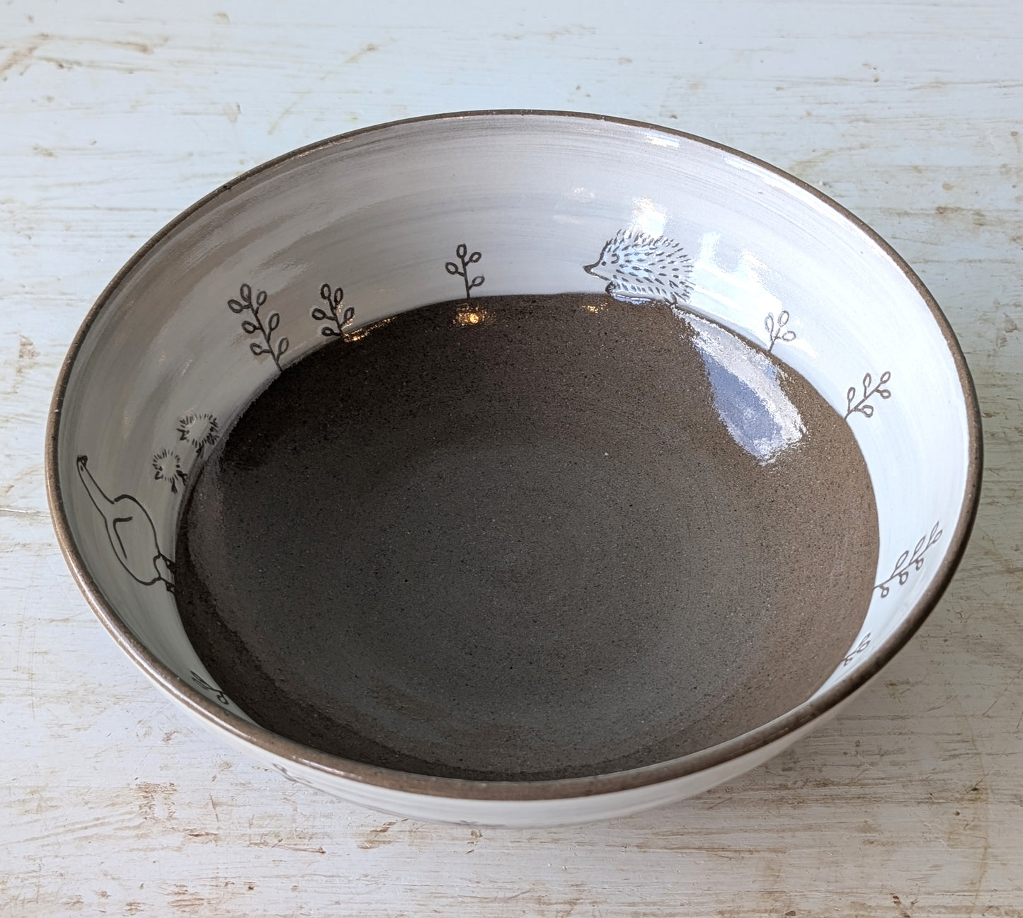 Ceramic bowl with hedgehog design on a light wooden surface