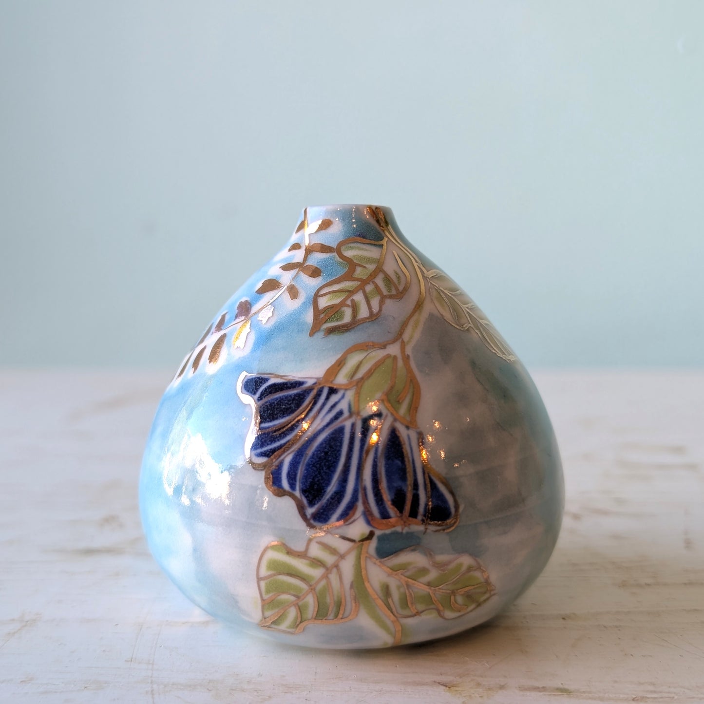 Decorative ceramic vase with batik floral patterns on a light surface and light blue background