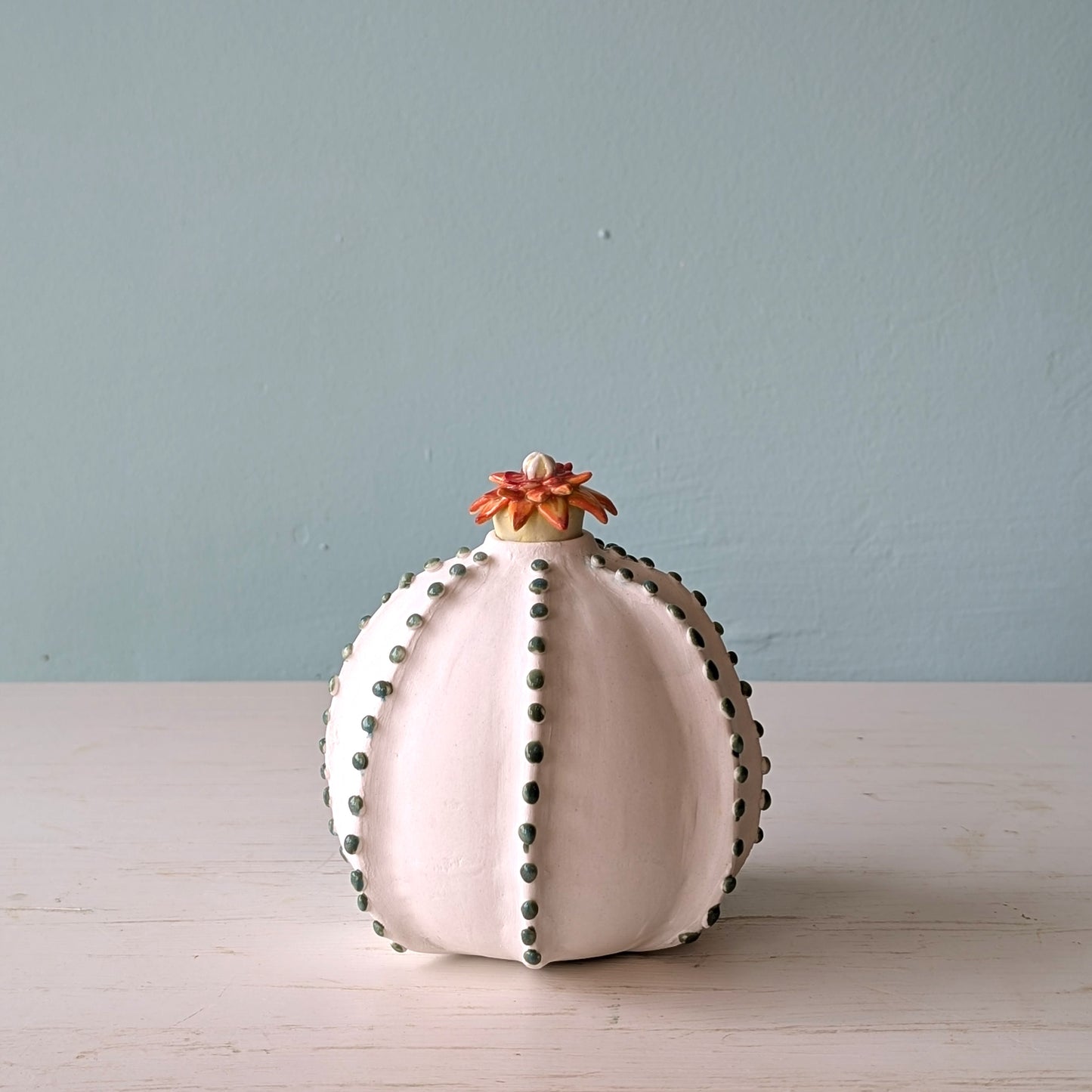 Decorative vase with floral top on a light surface against a light blue wall