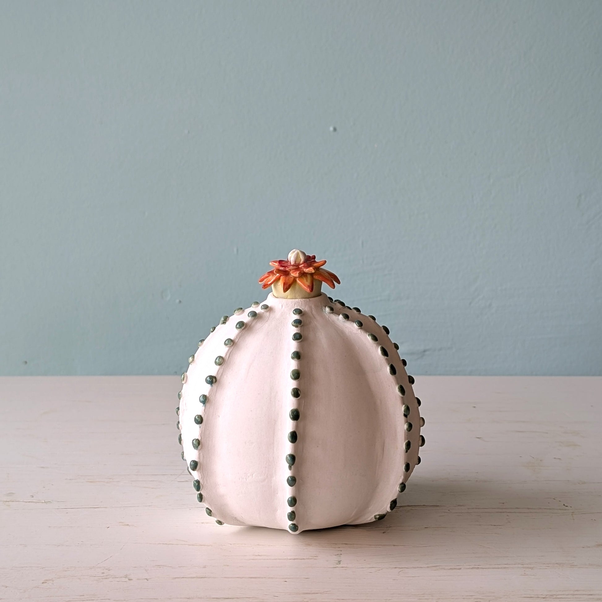 Decorative vase with floral top on a light surface against a light blue wall