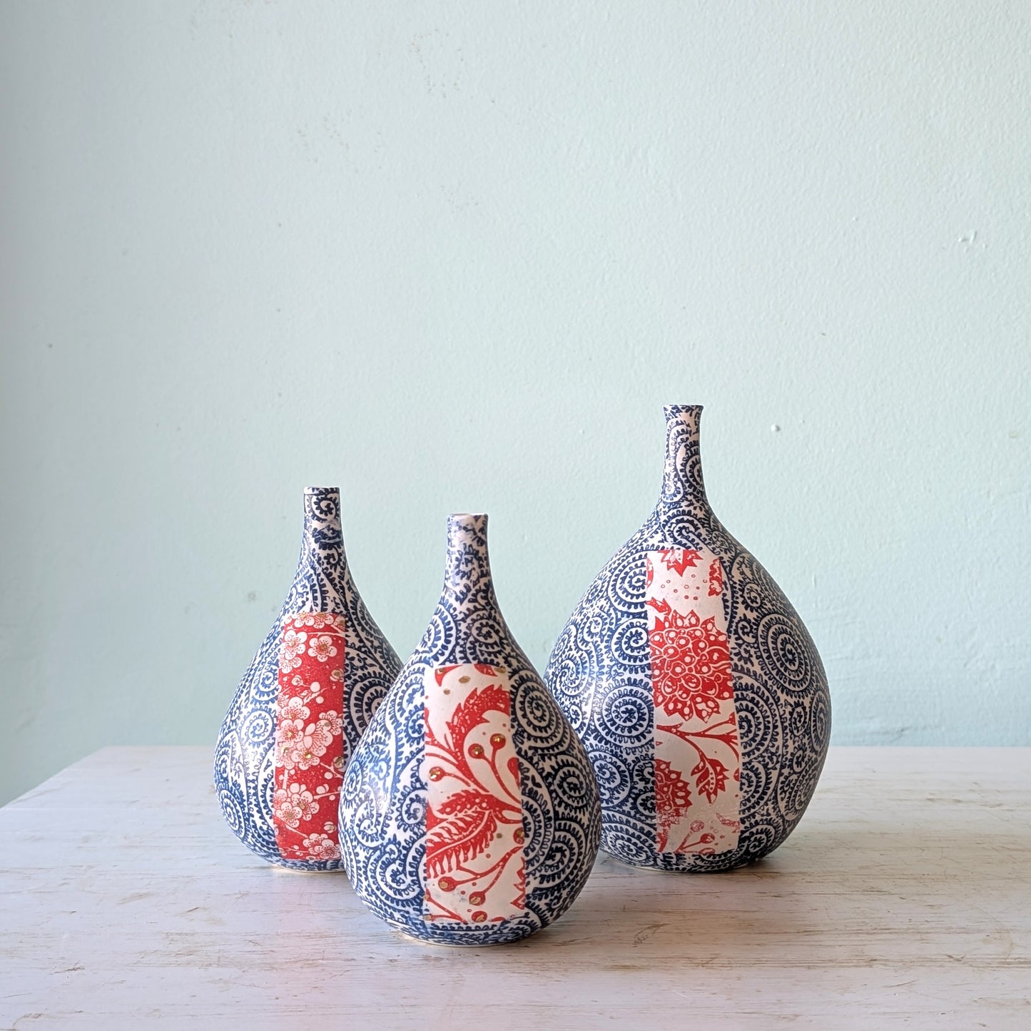 Three ceramic vases with red and blue floral decal and gold accents