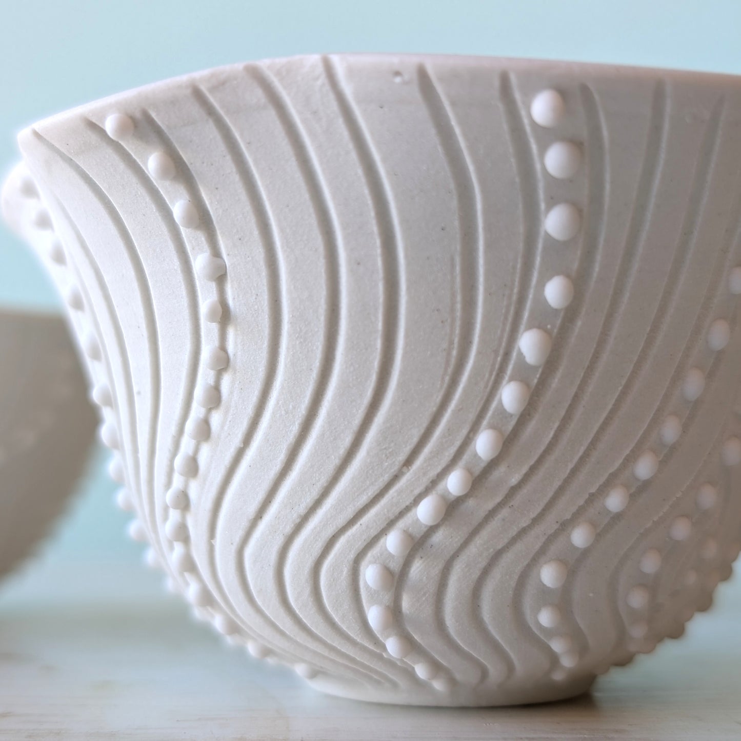 White ceramic bowl with textured design on a light blue background