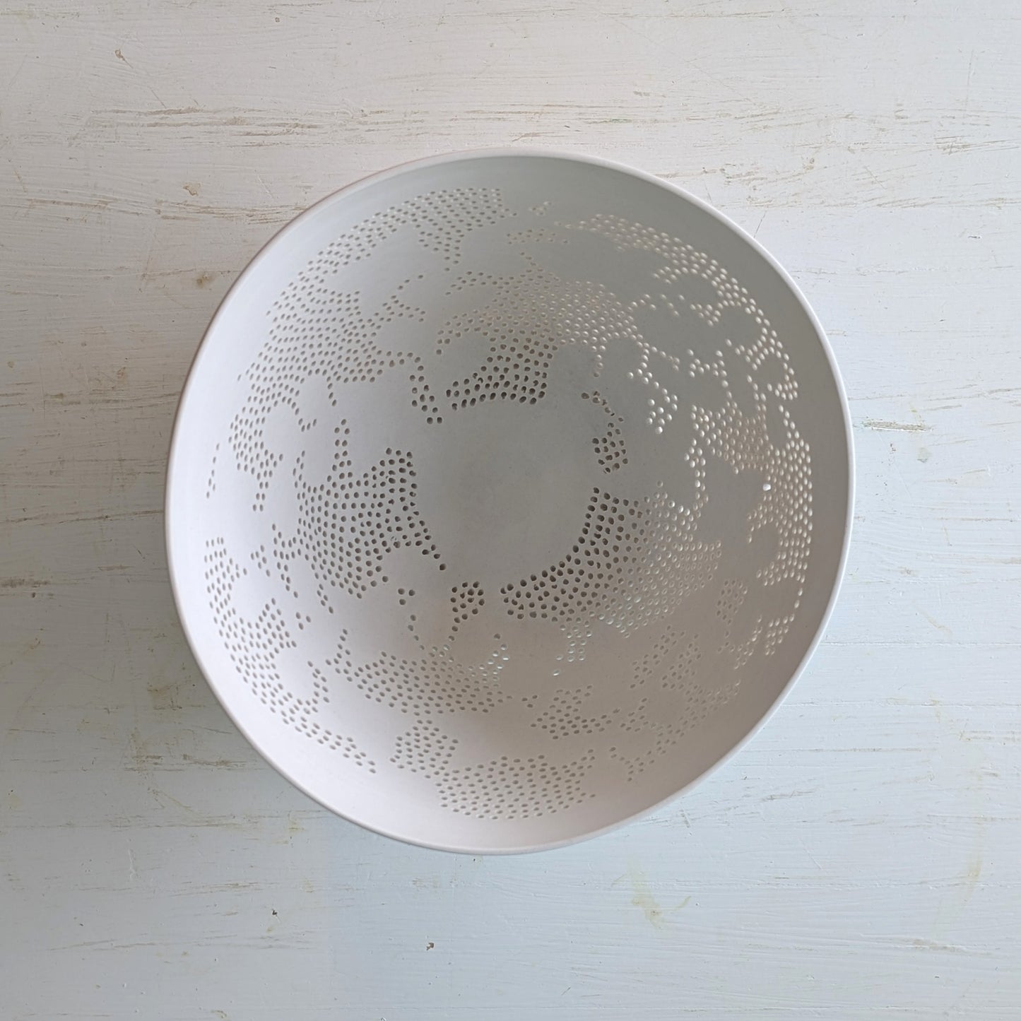 White ceramic bowl with decorative carved pattern on a light wooden surface