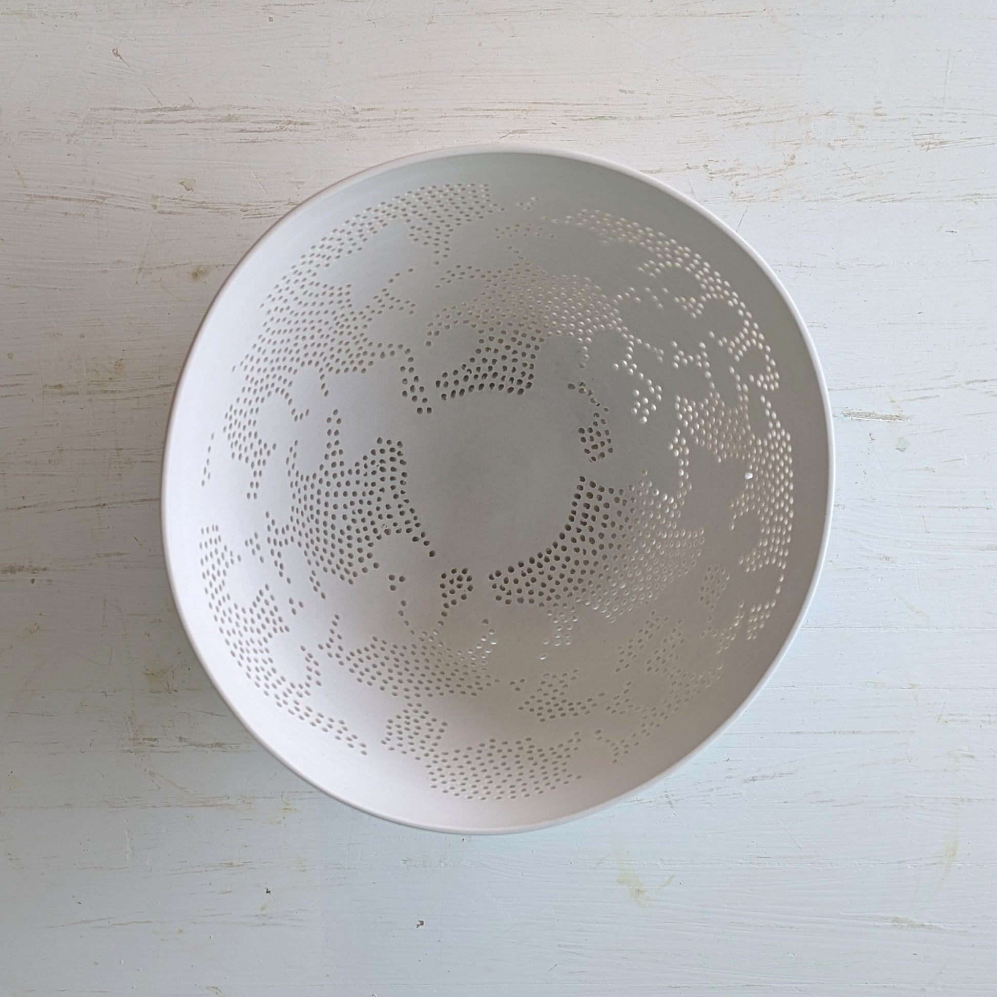 White ceramic bowl with decorative carved pattern on a light wooden surface