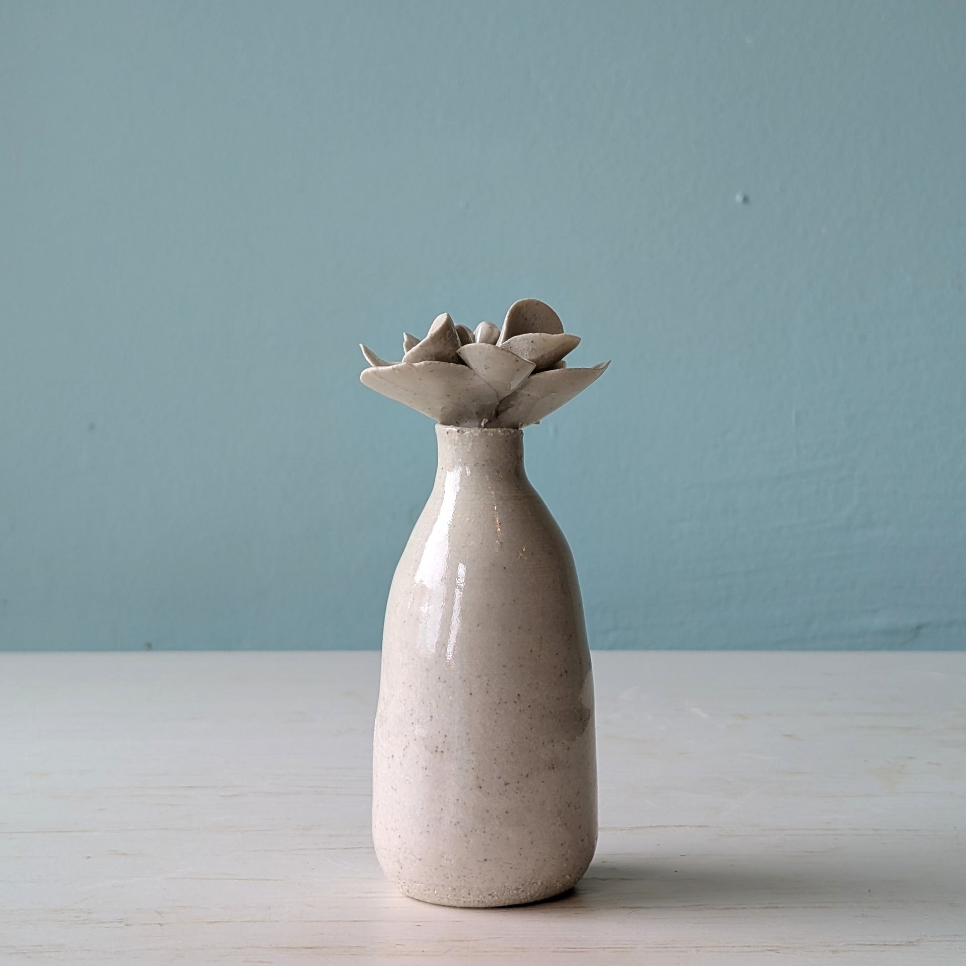 Ceramic bottle with a unique design on the lid on a light blue background