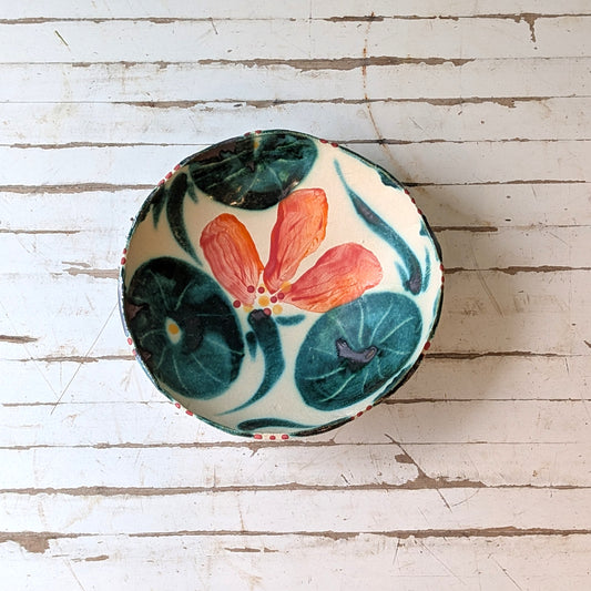 Top view of a white ceramic bowl with orange and green floral pattern.