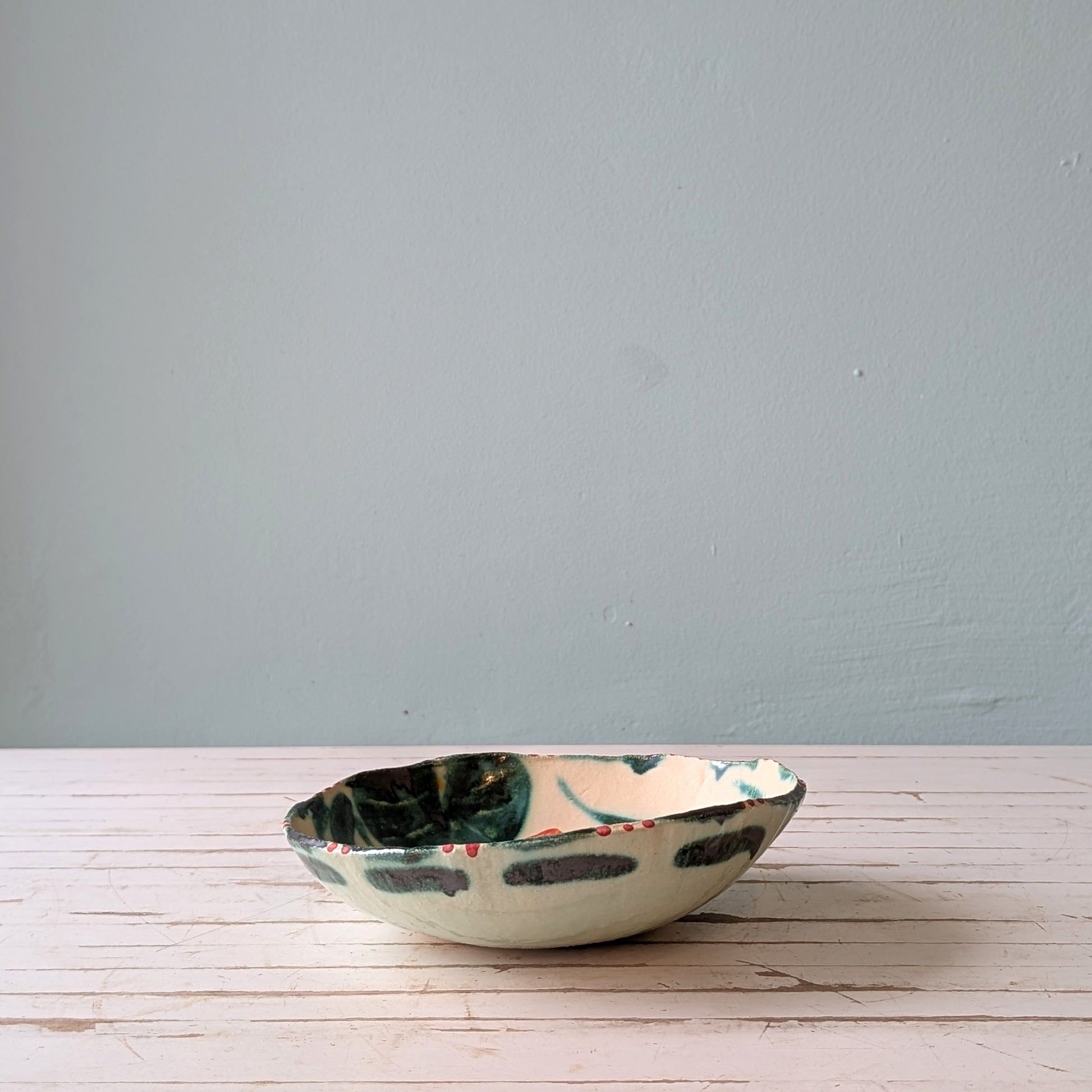 Ceramic bowl with floral patterns on a wooden surface and blue background.