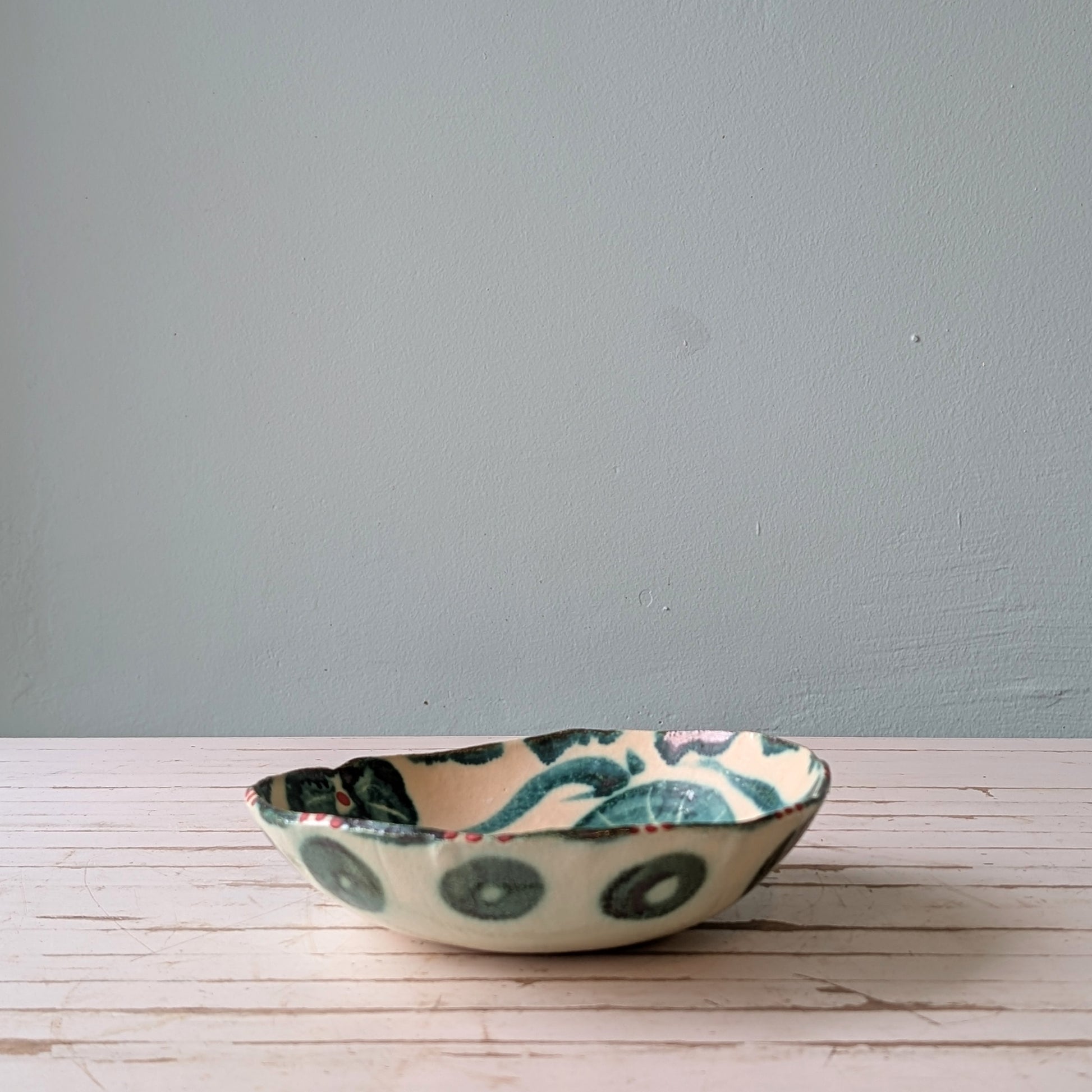 Ceramic bowl with a floral design on a wooden surface against a blue wall