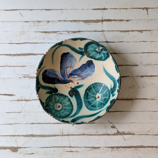Top view of a white ceramic bowl with blue and green floral design.