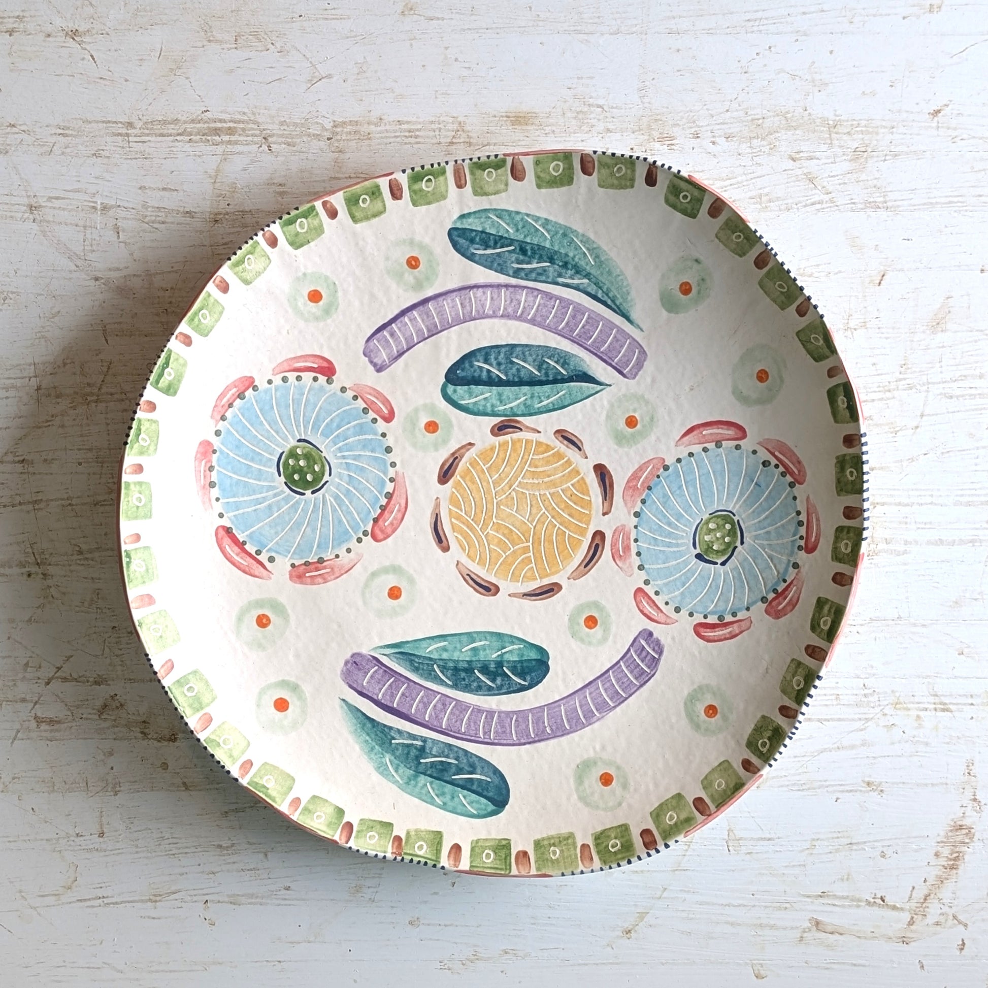 Decorative ceramic plate with colorful patterns on a light wooden surface
