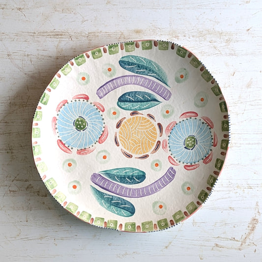 Decorative ceramic plate with colorful patterns on a light wooden surface
