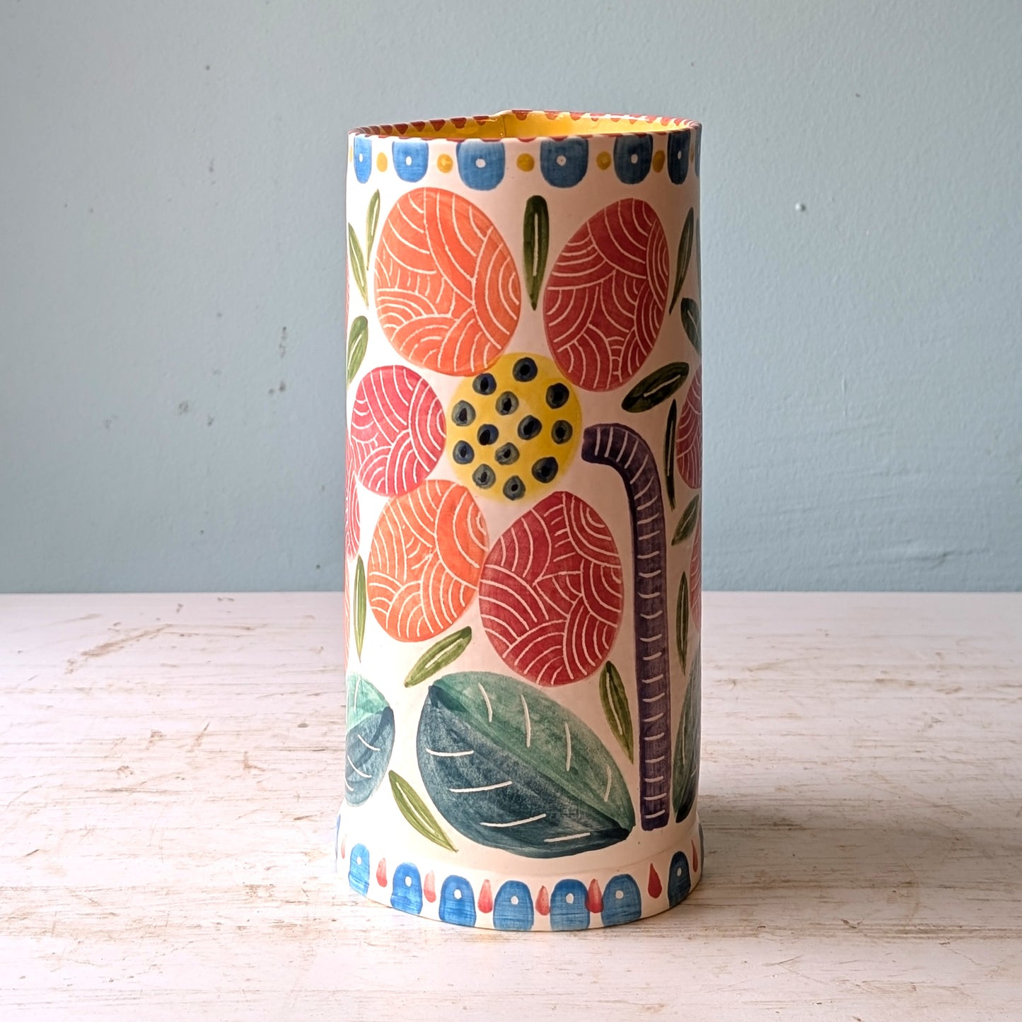 Decorative vase with floral pattern on a wooden surface and light blue background