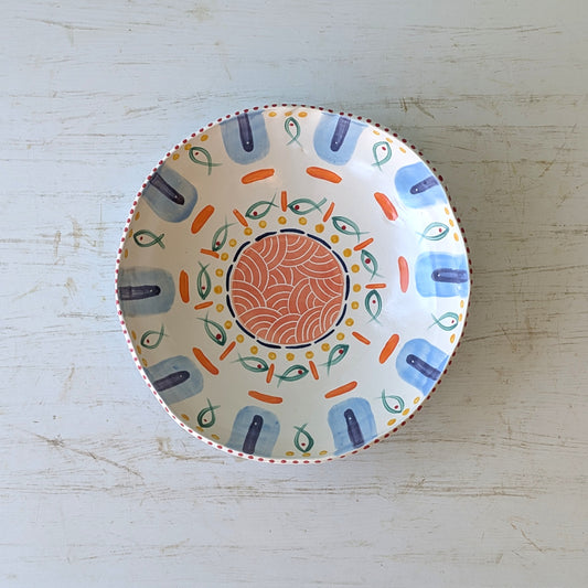 Ceramic bowl with abstract fish design on white table