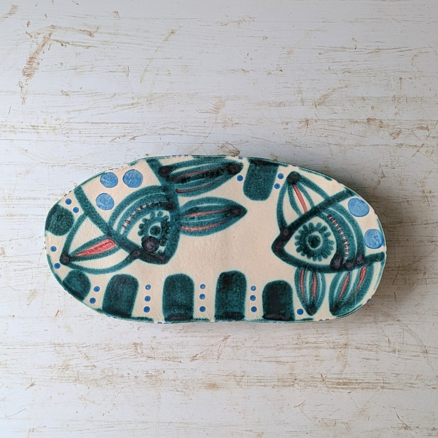 Ceramic dish with decorative fish design on a light wooden surface