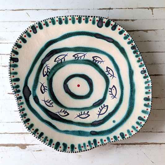 Top view of a white ceramic platter with green fish design and concentric circles.