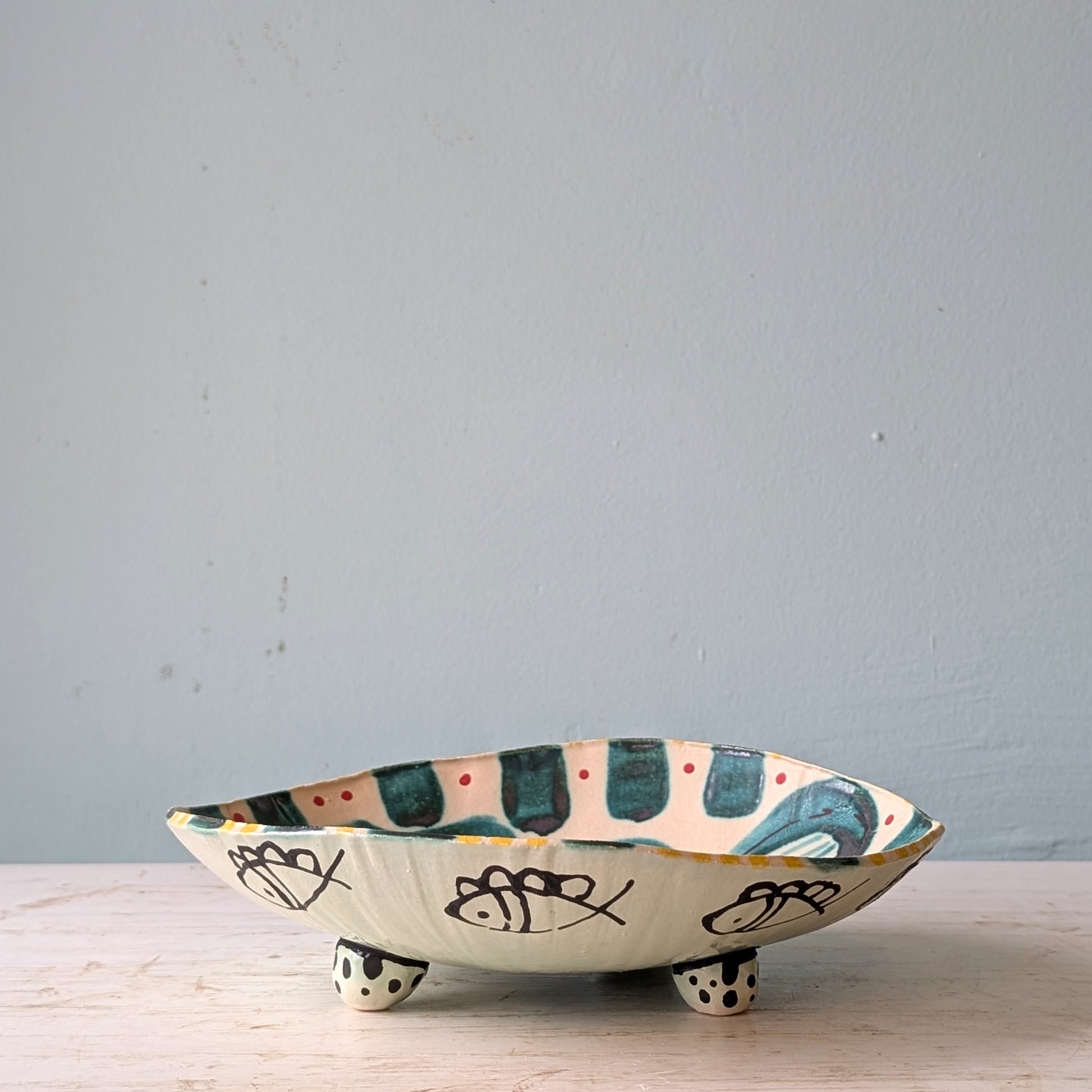 Ceramic bowl with decorative patterns on a light wooden surface and light blue background