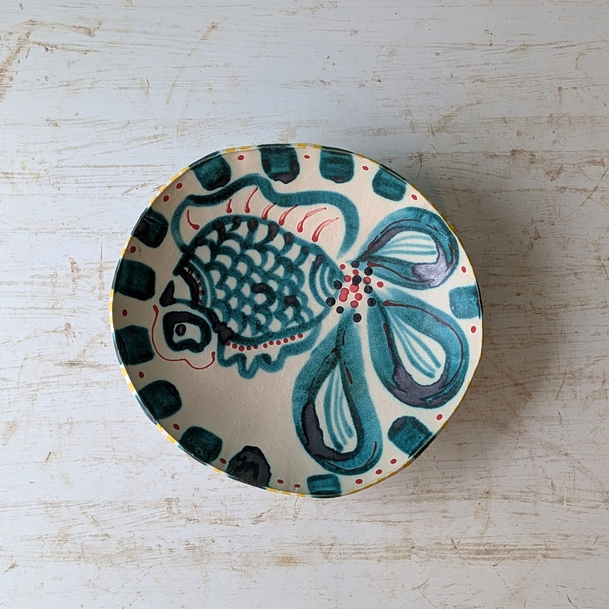 Ceramic bowl with fish design on a light wooden surface