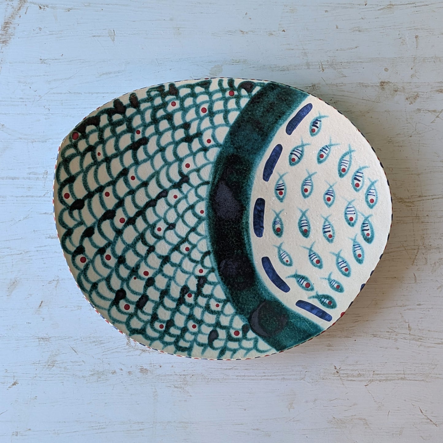 Ceramic platter with fish pattern on a light blue wooden surface