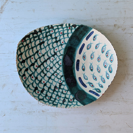 Ceramic platter with fish pattern on a light blue wooden surface