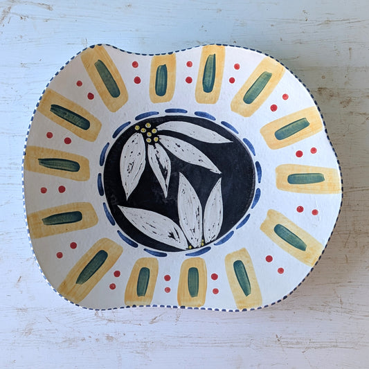 Decorative platter with floral design and colorful border on a light wooden surface