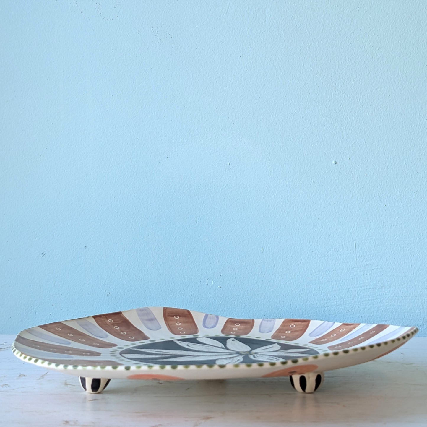 Ceramic platter with decorative patterns on a light blue background