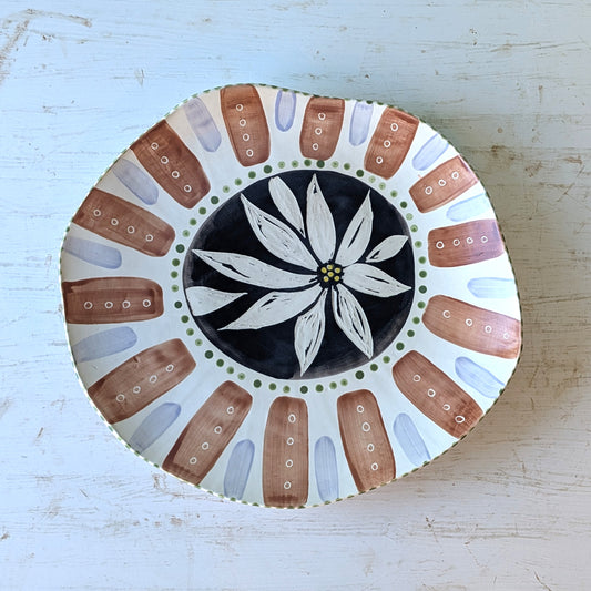 Brown, blue, black and white ceramic platter with floral pattern on a white wooden table