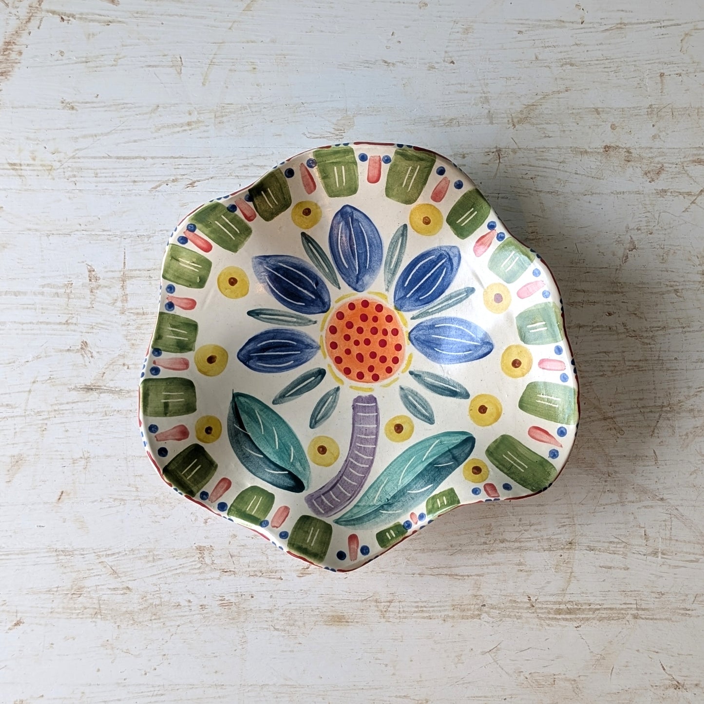 Decorative ceramic bowl with colorful floral design on a light wooden surface