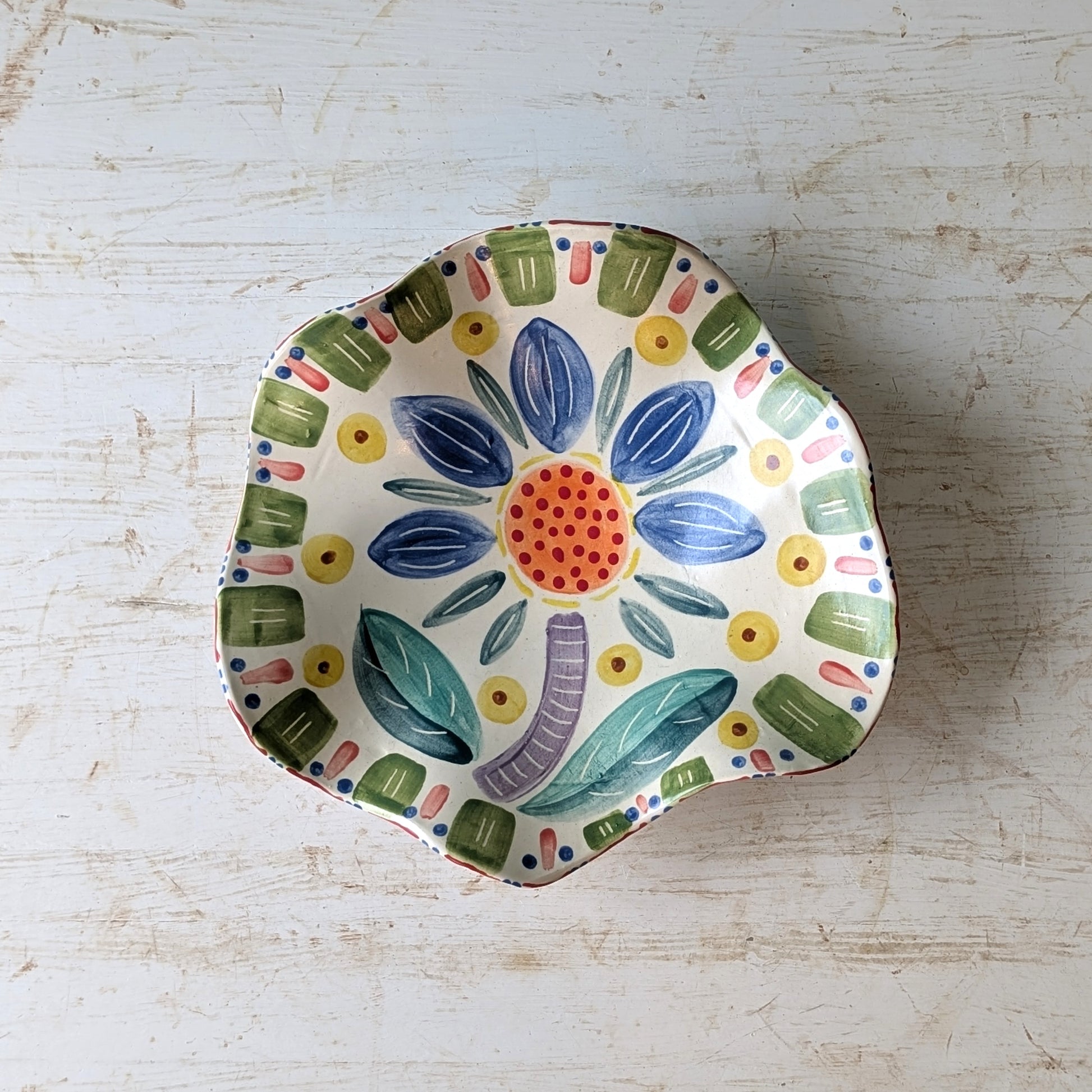 Decorative ceramic bowl with colorful floral design on a light wooden surface