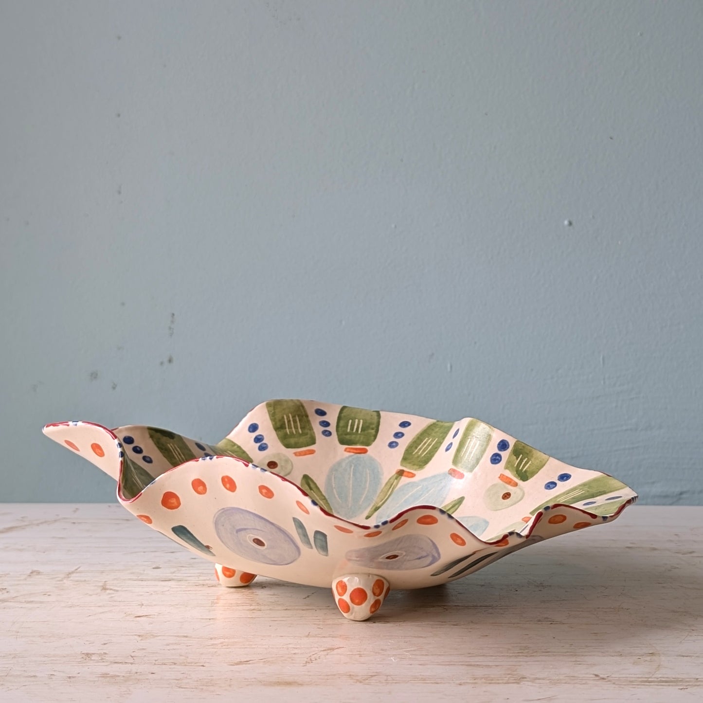 Decorative ceramic bowl with colorful patterns on a wooden surface and light blue background
