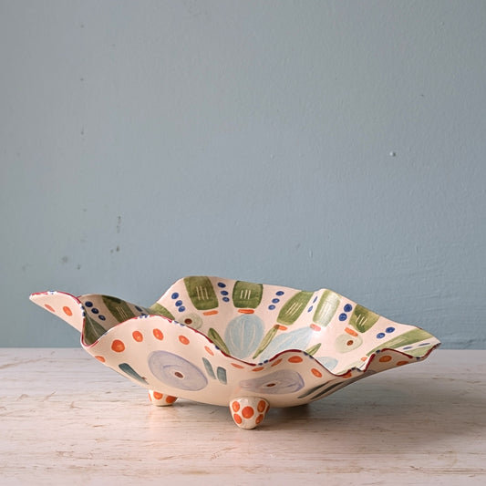Decorative ceramic bowl with colorful patterns on a wooden surface and light blue background