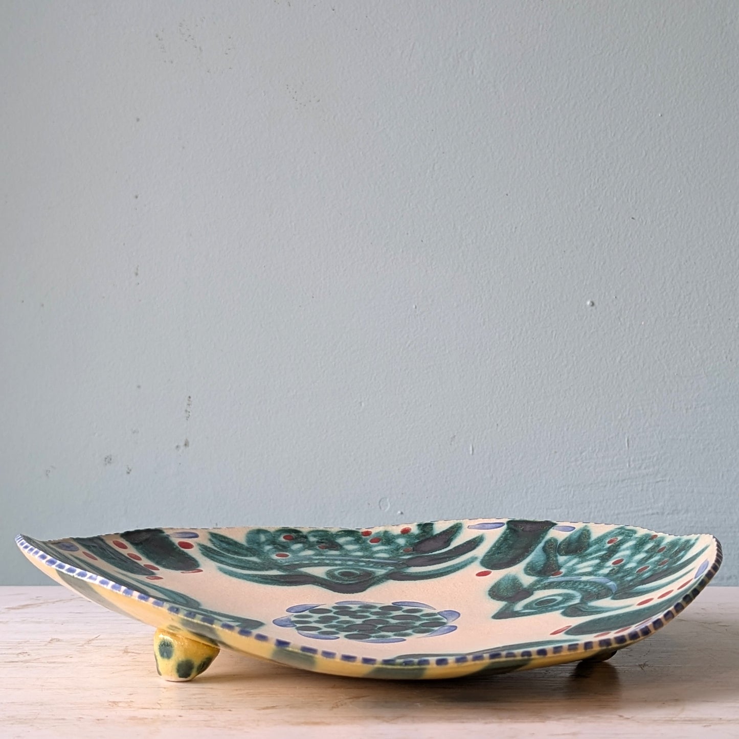 Ceramic platter with green floral pattern on a light gray background