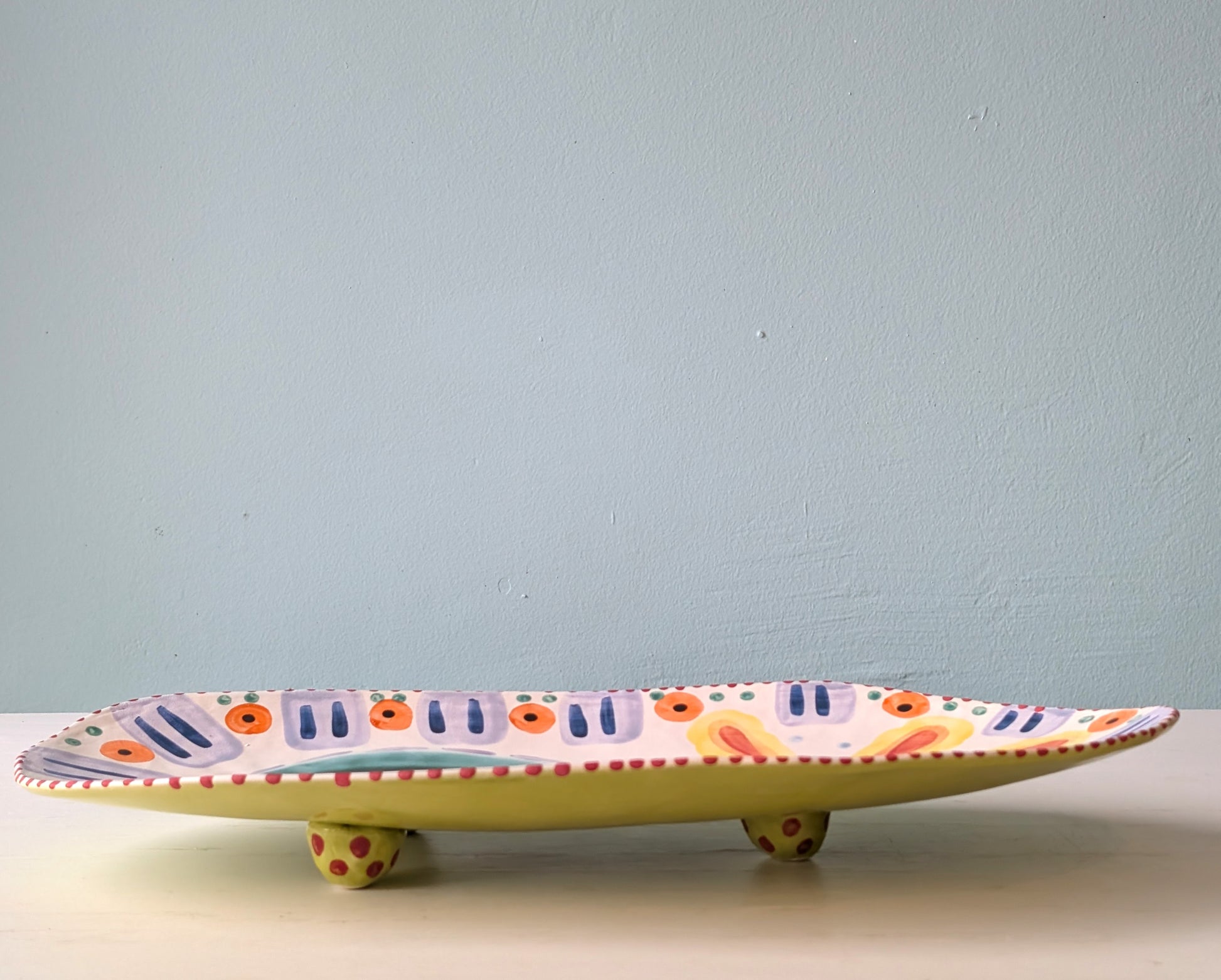 Decorative ceramic platter with colorful patterns on a light blue background